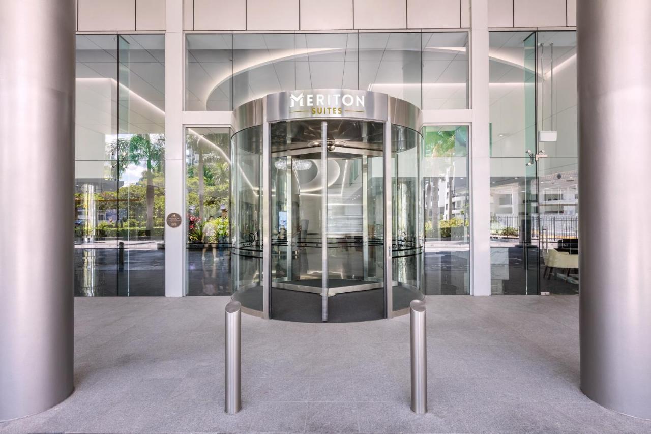 Meriton Suites Southport Gold Coast Buitenkant foto The photo shows the entrance to a building featuring a revolving door made of glass and metal. The door is labeled "MERRION SUITES." The interior space is visible through the glass facade, revealing a modern and well-lit environment with sleek design