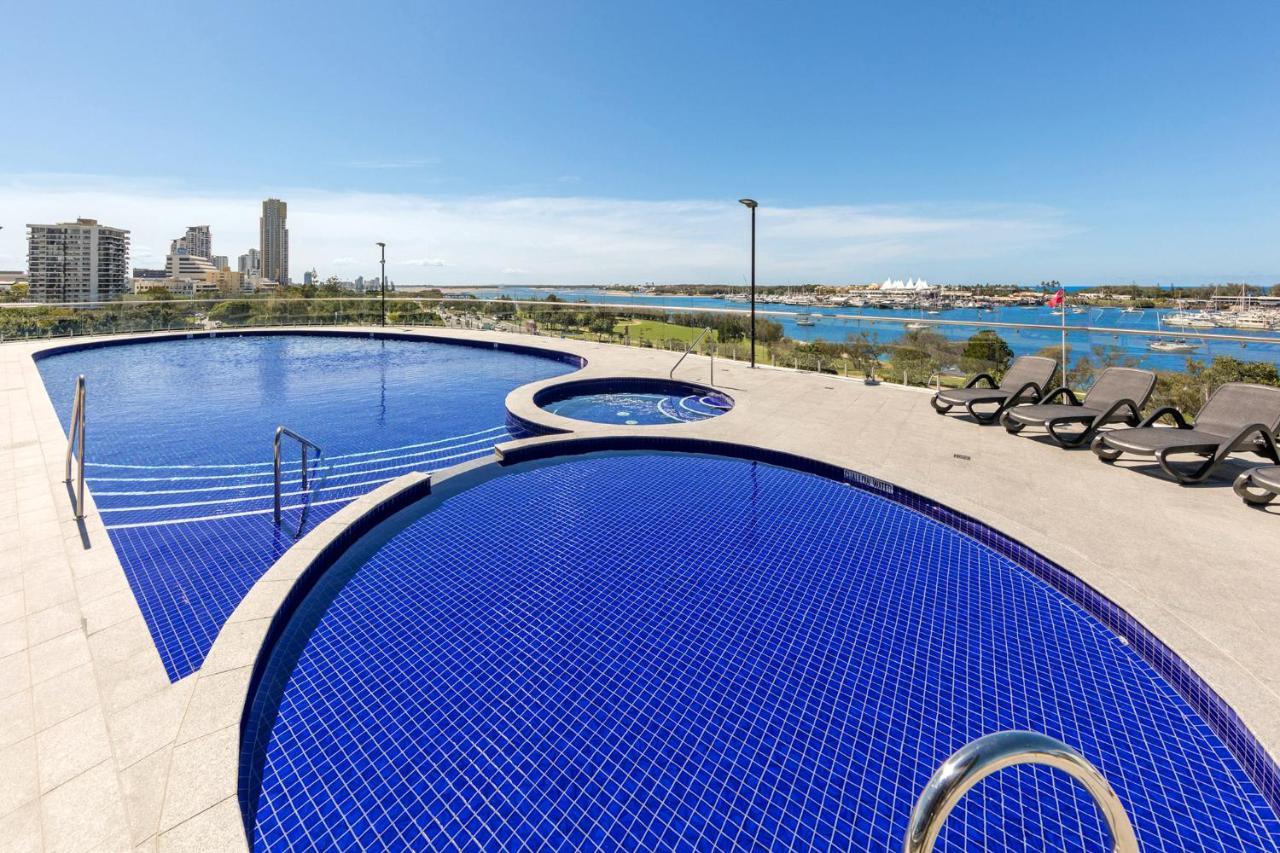 Meriton Suites Southport Gold Coast Buitenkant foto The photo shows a beautiful outdoor swimming pool area featuring two circular pools. The larger pool has a vibrant blue tiled surface and steps leading into it. Adjacent to it, there is a smaller round pool, likely a hot tub. Surrounding the pools ar